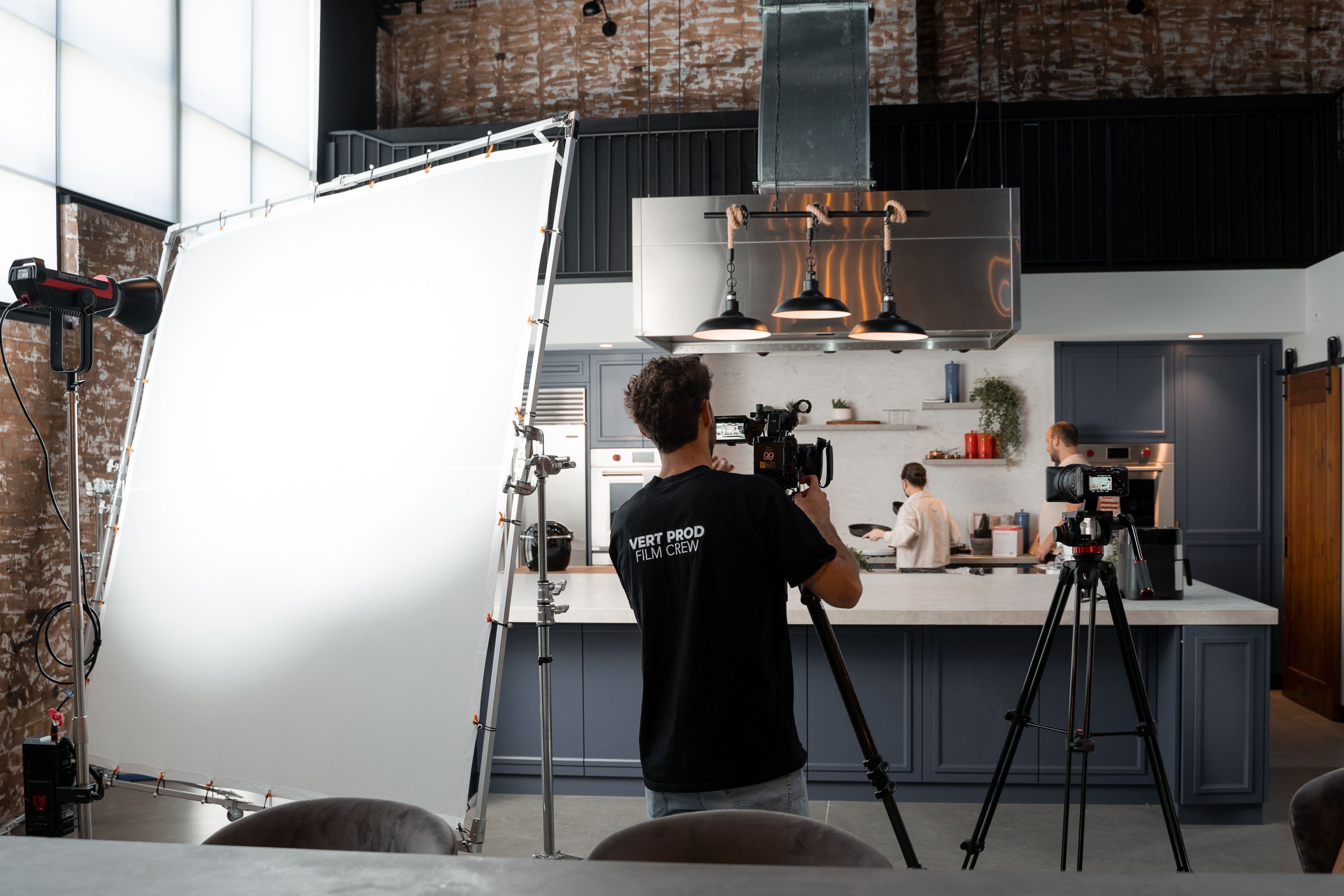 Professional camera and lighting crew preparing a modern kitchen studio